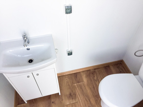 Toilette, Waschbecken und Elektroheizung in einem Conliving-Sanitärcontainer.