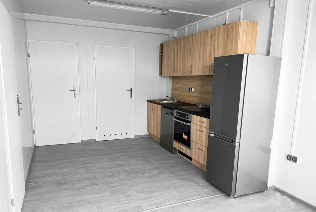 Küchenzeile mit Kühlschrank, Kochfeld und Waschbecken in der Wohncontaineranlage in W7-2 & W6.